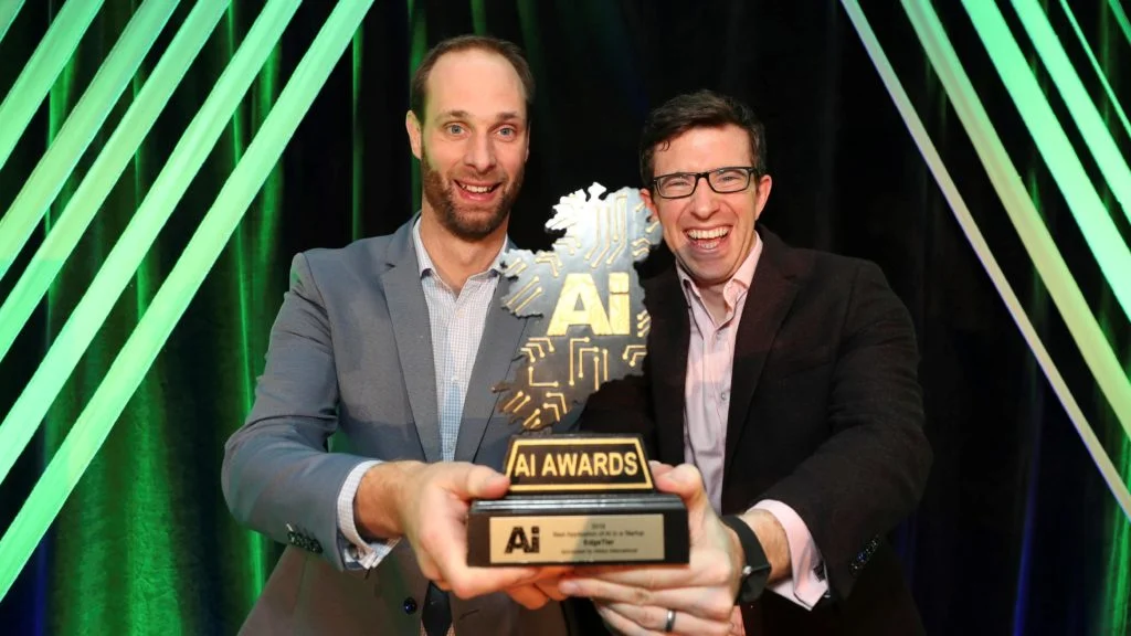 Two people hold an AI Awards trophy at the 2018 ceremony.