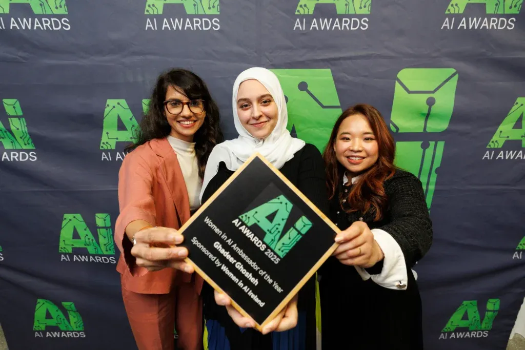 Three people celebrate with the 2025 Women in AI Ambassador of the Year award.